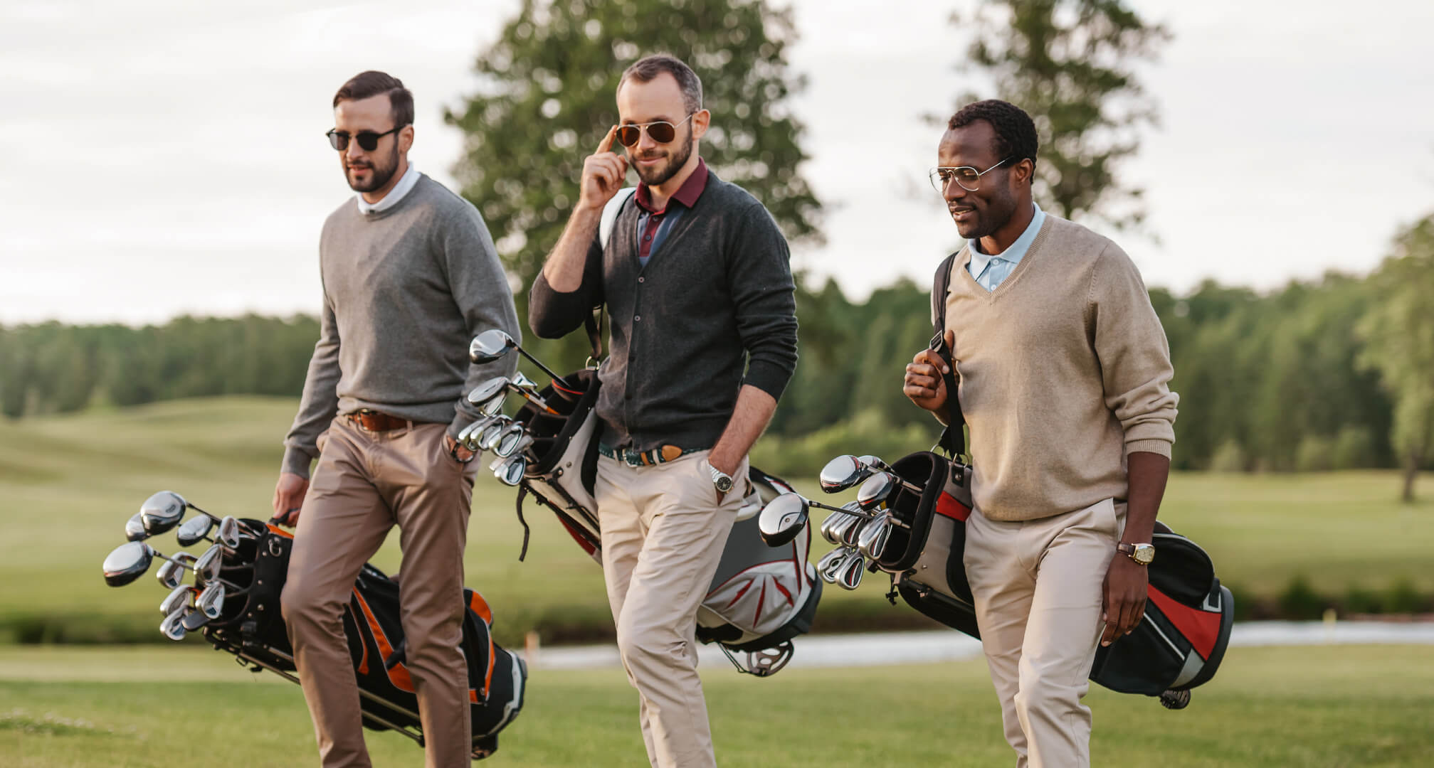 tre personer spiller golf med solbriller og golfbags