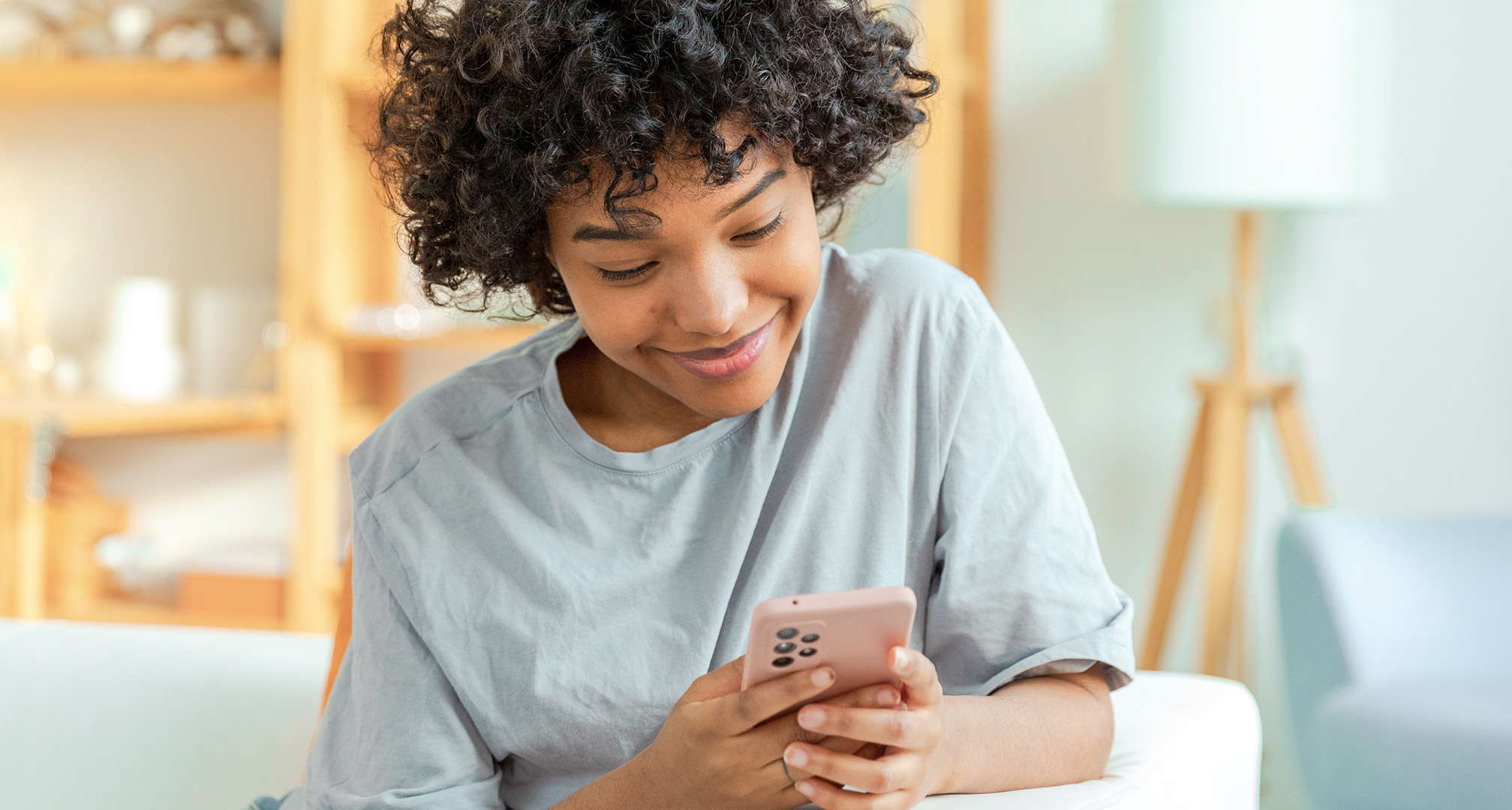 nærbillede af en person, der smiler og kigger på mobiltelefon