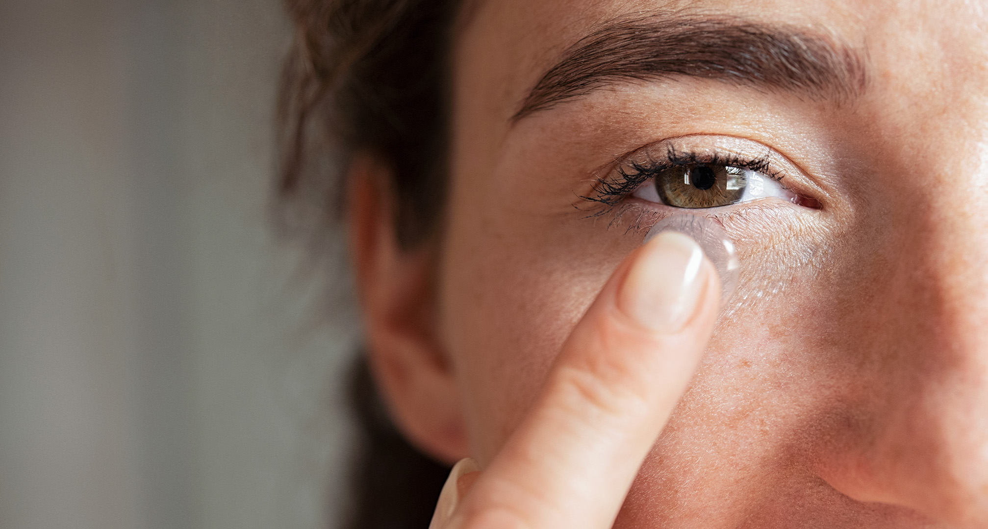 nærbillede af en person, der holder en kontaktlinse foran øjet 