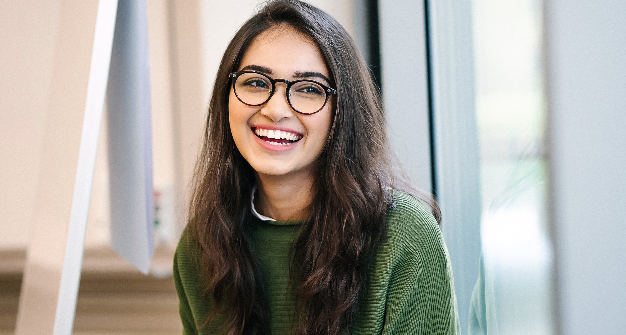 foto af en smilende person med langt hår og sorte brillestel