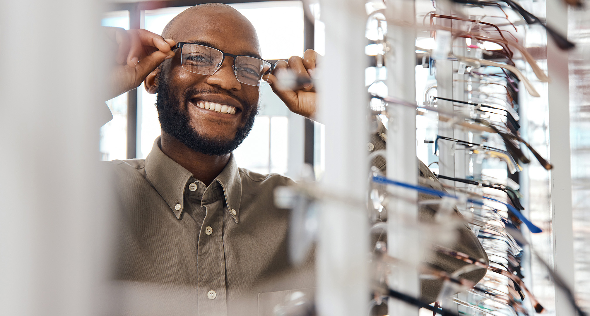 foto af smilende person, der prøver briller hos optikeren